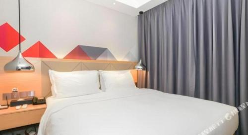 a bedroom with a large white bed and a window at Borrman Hotel Zhuhai Gongbei Port Fuhuali Light Rail in Zhuhai