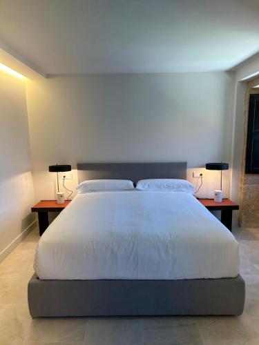 a bedroom with a large bed with two lamps on two tables at Arume Rural House in Catasueiro
