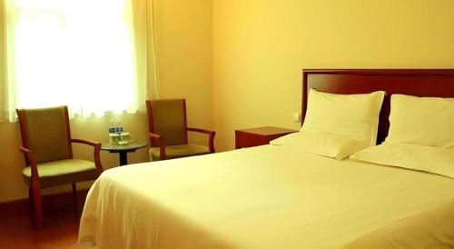 a bedroom with a white bed and two chairs at GreenTree Inn Langfang Sanhe South Yingbin Road Express Hotel in Sanhe