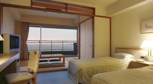 a hotel room with two beds and a balcony at Hotel Harvest Nankitanabe in Tanabe