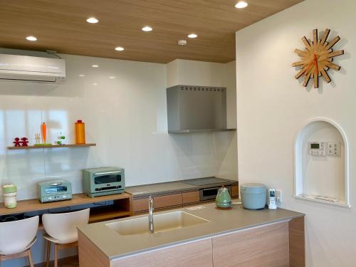 a kitchen with a sink and a clock on the wall at マール淡路島ラグジュアリービーチリゾート in Awaji