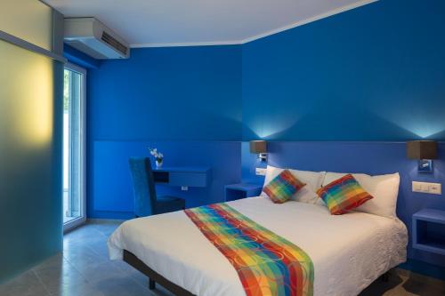 a blue bedroom with a bed with a colorful blanket at Hotel Liberty Self Check-In in Bellinzona