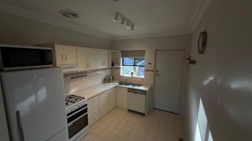 a kitchen with white cabinets and a sink and a microwave at 2 Bdrm Walkerville Apartment - Spacious, ducted heating & cooling, centerally located! in North Adelaide