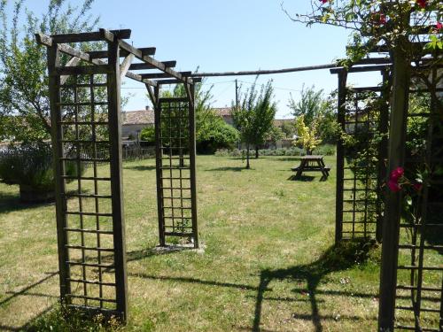 an outdoor garden with an arch and a picnic table at Le Petit Souhait & Le Verger in Gourvillette