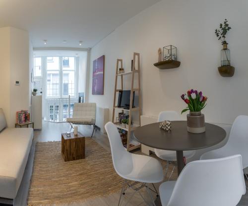 un soggiorno con tavolo e sedie bianche di Luxury Flower Market Apartment ad Amsterdam