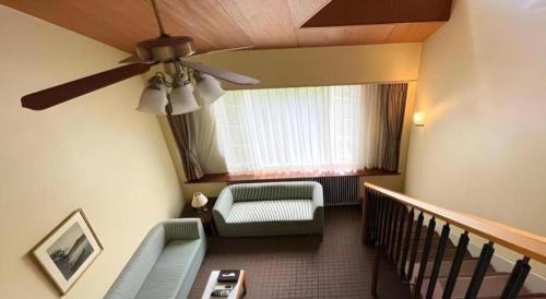 a living room with a ceiling fan and a couch at Fuji Shoei kaikan in Fuji