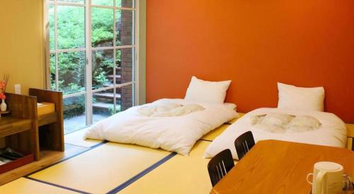 two beds in a room with a table and a window at Fuji Shoei kaikan in Fuji
