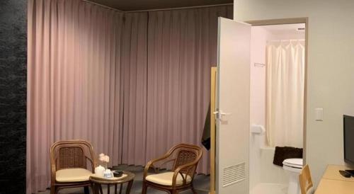 a room with two chairs and a table with a television at Fuji Shoei kaikan in Fuji