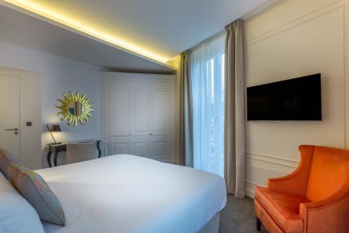 a bedroom with a bed and a chair and a television at Hôtel La Comtesse in Paris