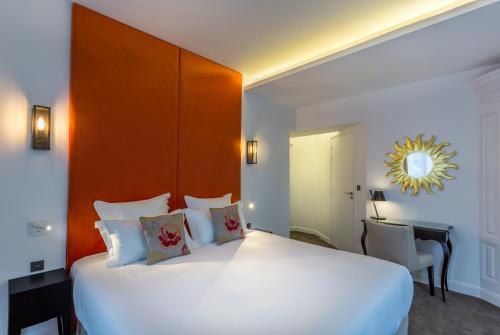 a bedroom with a large white bed with a wooden headboard at Hôtel La Comtesse in Paris