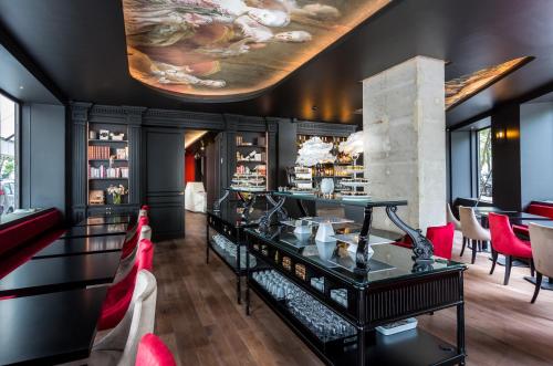 un restaurant avec un bar et des chaises rouges dans l'établissement Hôtel La Comtesse, à Paris