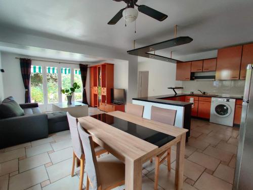Il dispose d'une cuisine et d'un salon avec une table et des chaises en bois. dans l'établissement Bas de villa indépendant. 10min de la mer, à Biot