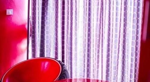 a window with a red chair in front of a curtain at The B Ranong Trend Hotel in Ranong
