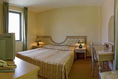 a bedroom with a bed and a desk and a window at Hotel Bordo in Plovdiv