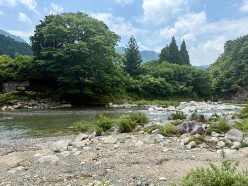 a river with rocks and trees in the background at リバーサイドグランピングNuts in Higashiomi