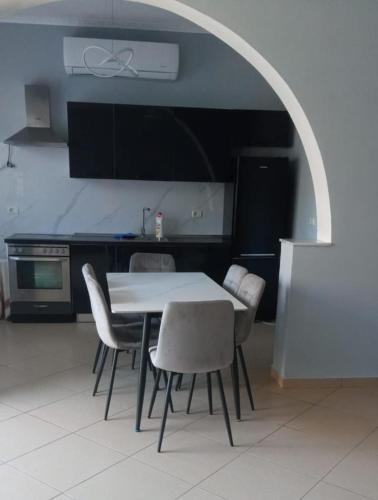a kitchen with a white table and chairs in a room at Hidden Gem Vlora in Vlorë