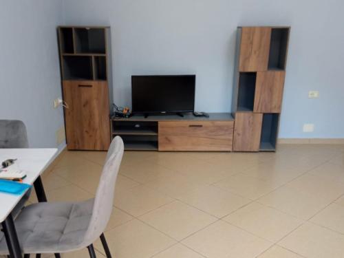 ein Wohnzimmer mit Fernseher, Tisch und Stühlen in der Unterkunft Hidden Gem Vlora in Vlorë