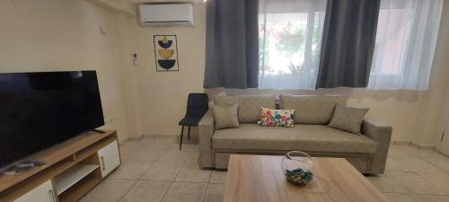 a living room with a couch and a tv at Harmony 1 in Áyios Spirídhon