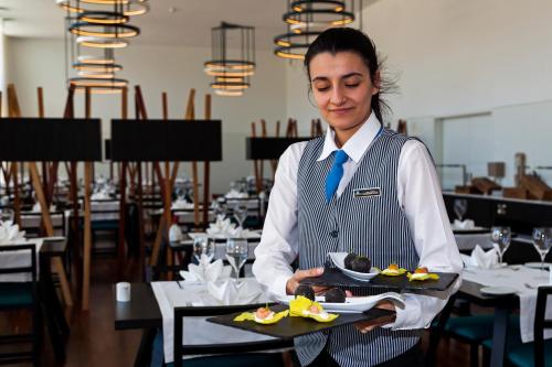 a woman holding a plate of food in a restaurant at Douro Royal Valley Hotel & Spa in Riba Douro