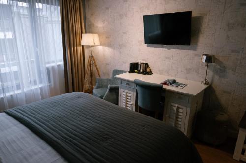 a bedroom with a bed and a desk with a television at Hotel Cocoon in Ostend