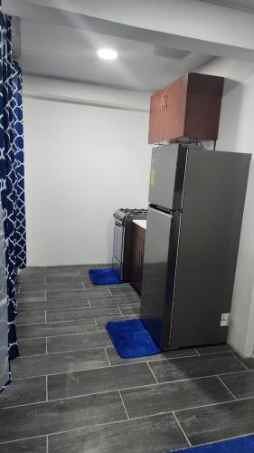 a kitchen with a refrigerator and blue mats on the floor at Hodgson residents in La Ceiba