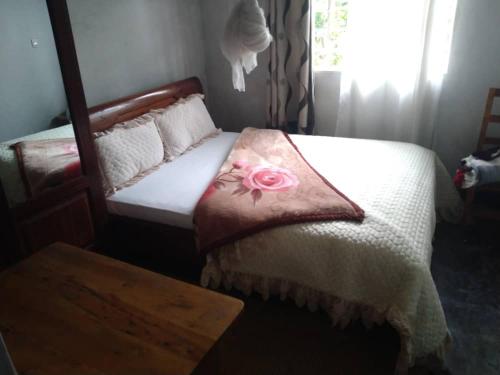 a bedroom with a bed with a rose pillow on it at La paillotte gorilla place kinigi in Kinigi
