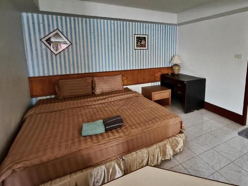 a bedroom with a bed and a dresser and a night stand at Naza Orchid Pattaya in Pattaya South