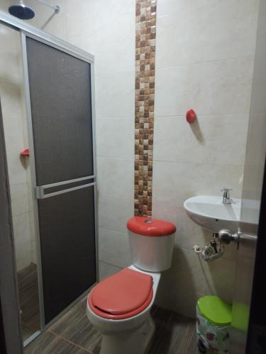 a bathroom with a red toilet and a sink at Lila Alojamiento Campestre in Melgar