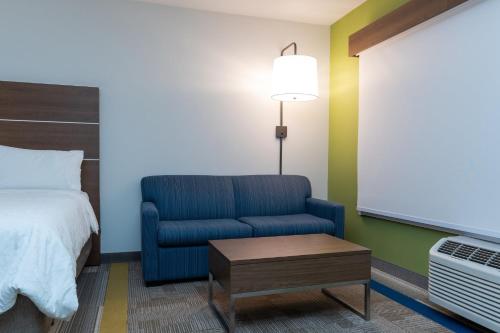 a room with a bed and a blue chair and a table at Holiday Inn Express & Suites - Edmonton SW – Windermere by IHG in Edmonton