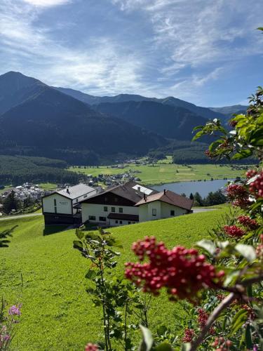 a green field with houses and a lake and mountains at Berghotel Plagött in San Valentino alla Muta