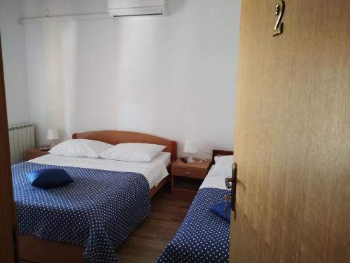 a bedroom with two beds with blue sheets and a door at Krka Ivan in Lozovac