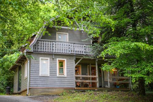 a small gray house with a balcony in the woods at Nomád Glamping in Noszvaj