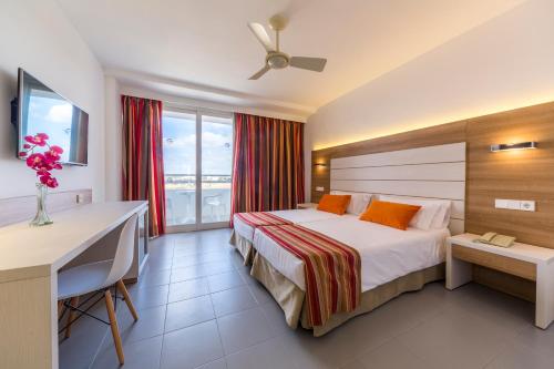 ein Hotelzimmer mit einem Bett, einem Schreibtisch und einem Fenster in der Unterkunft Globales Mediterrani in Cala Blanca