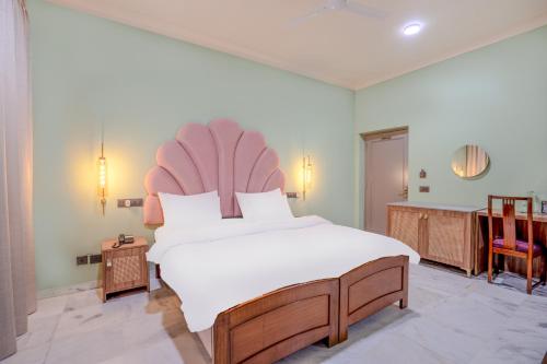 a bedroom with a large white bed with a pink headboard at Girisadan Boutique Stay in Jaipur