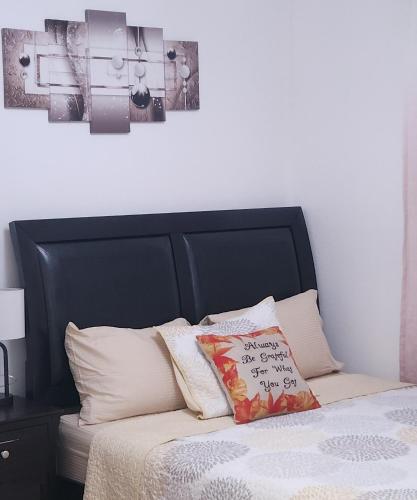 a bed with a black headboard and some pillows at Abby's Comfort in North Woodmere