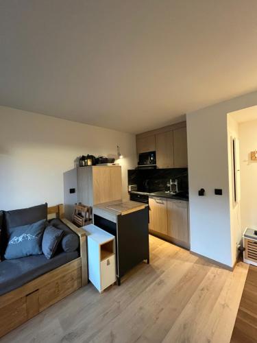 un salon avec un canapé et une cuisine dans l'établissement Appartement LA PLAGNE plein sud au pied des pistes, piscine et parking gratuits, à La Plagne Tarentaise