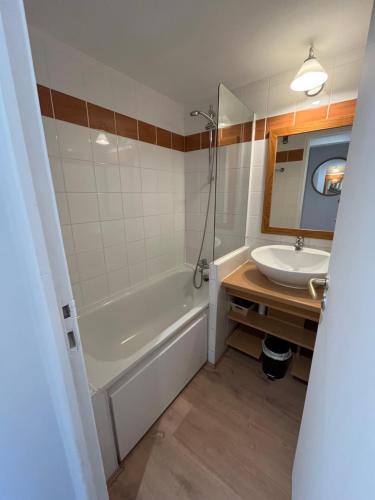 une salle de bain avec une baignoire et un lavabo dans l'établissement Appartement LA PLAGNE plein sud au pied des pistes, piscine et parking gratuits, à La Plagne Tarentaise