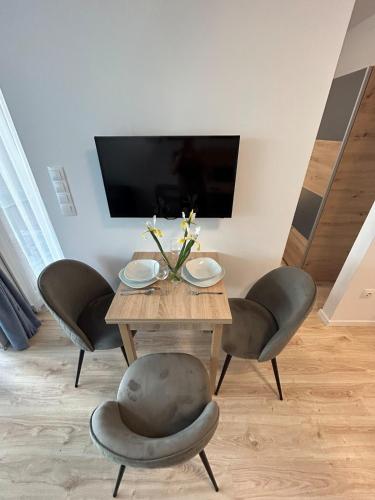 a dining room with a table with chairs and a television at Ponton Apartman Alsóőrs in Alsóörs