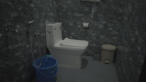 a bathroom with a toilet and a blue bucket at AppleLand City Athirapilly by Hotels Cart in Athirappally