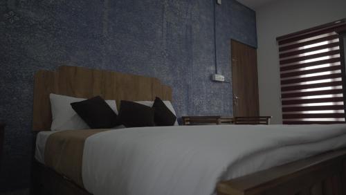 a bedroom with a large white bed with black pillows at AppleLand City Athirapilly by Hotels Cart in Athirappally