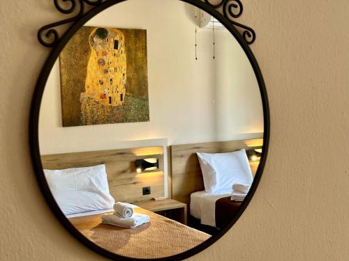 a mirror reflecting a bedroom with a bed and a painting at Dili Apartments in Ierissos