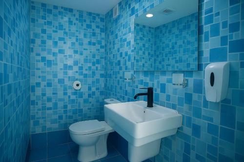 a blue tiled bathroom with a toilet and a sink at Korogwe Comfort Hotel in Nkunjila