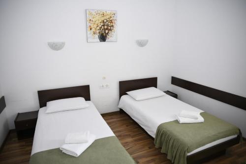 two beds in a room with white walls and wood floors at Pensiunea Zbor in Cluj-Napoca