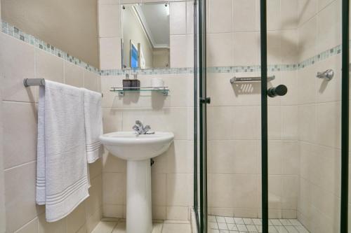 a bathroom with a sink and a shower at Fort Totten Villas in Gaborone