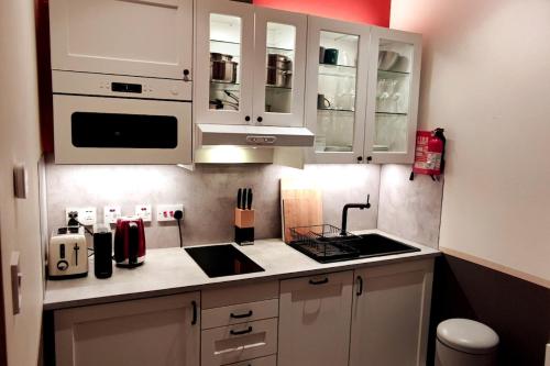 a kitchen with white cabinets and a sink at Comfortable flat in a very historic part of London in London