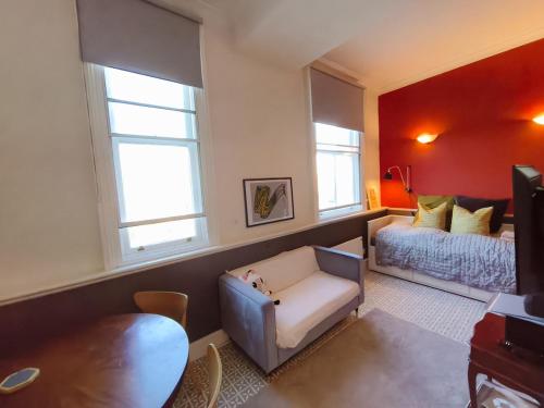 a living room with a bed and a couch and windows at Comfortable flat in a very historic part of London in London