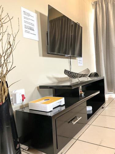 a black desk with a television on top of it at Family Room Libem Lodge in Edenvale