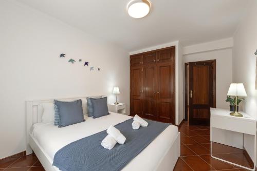 a bedroom with a large white bed with towels on it at Papoa Beach House in Peniche