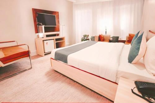 ニューデリーにあるAIRPORT HOTEL Almati EN With Free Airport Pickup Delhi Airportの大きな白いベッドとテレビのある寝室