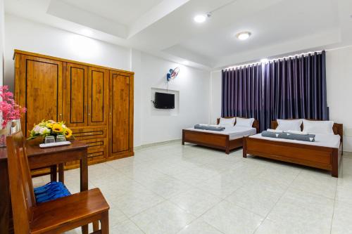 a living room with two beds and a tv at Hoa Cúc Phương Hotel Dĩ An - Bình Dương in Dĩ An